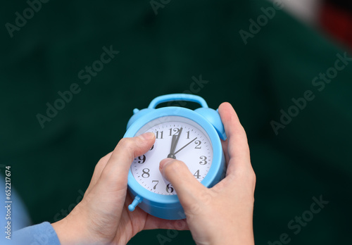 Zegar budzik wskazujący północ trzymany w dłoniach, zmieniać czas photo