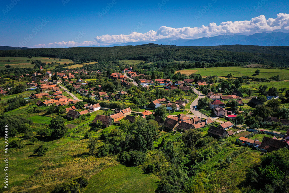 Obraz premium Drone photograph of Somartin old saxon village in Transylvania. Fagaras Mountains in the background.