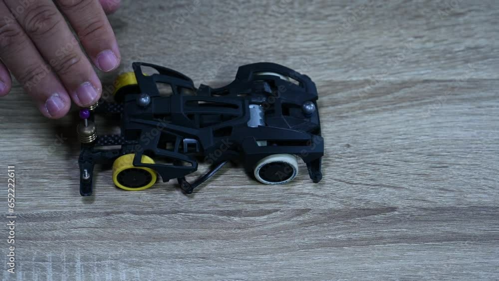 Checking the alignment and balance of a Tamiya Mini sports car by dropping it again and again on a table inside a shop in Bangkok, Thailand.