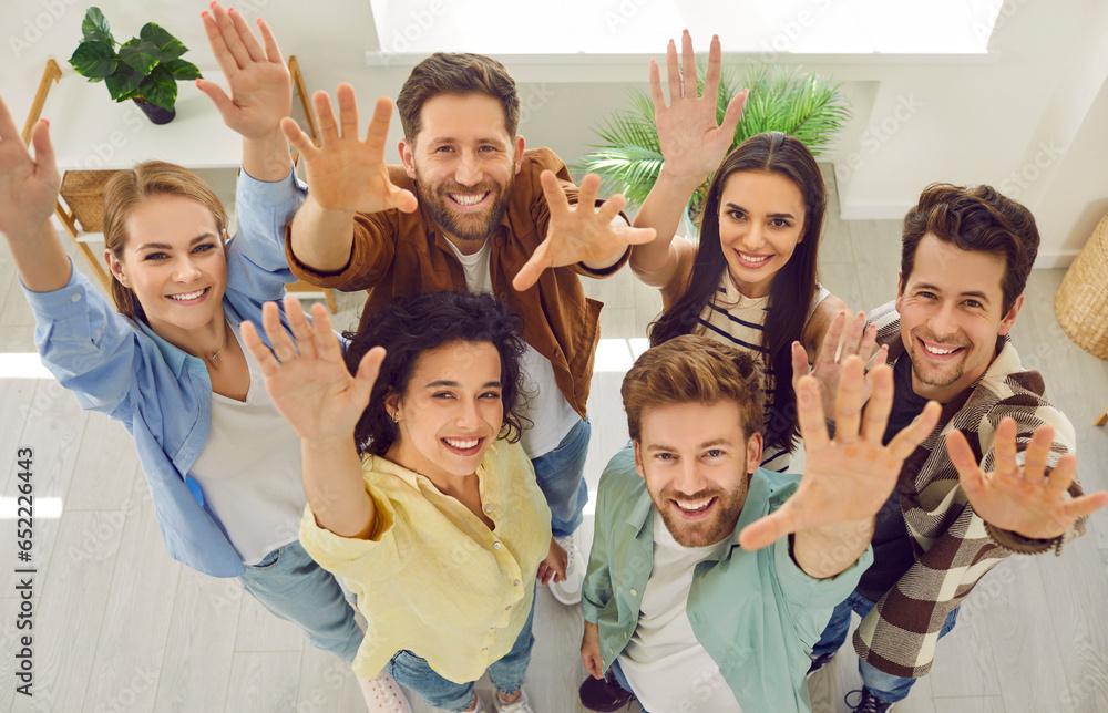 Naklejka premium High angle top view from above group portrait team happy smiling young coworker friend people standing in office looking up waving hand saying hello inviting new members to business leader forum event