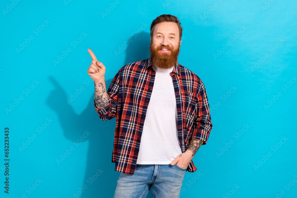 Photo of positive good mood man dressed plaid shirt pointing finger empty space isolated blue color background Photo of positive good mood man dressed plaid shirt pointing finger empty space isolated blue color background