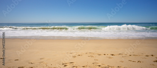 Conceptual background for power, might, strength. Mighty strong waves roar as they constantly crash onto sandy beach.Panorama of sky sea waves sand beach.