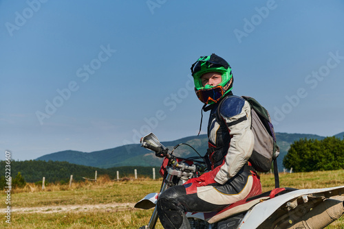 Fototapeta Naklejka Na Ścianę i Meble -  A professional motocross rider, fully geared up with helmet, gloves, and goggles, sits poised on their motorcycle, ready to embark on a thrilling training session through the challenging forest