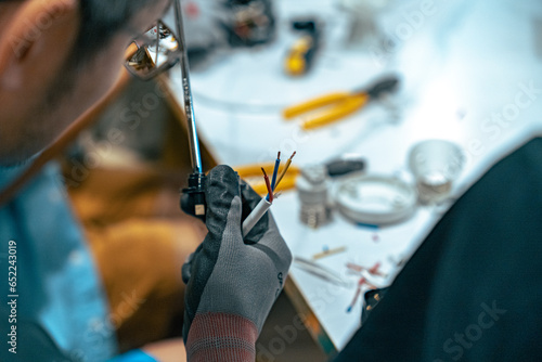 Asian man repairing a wire cable with work gloves close up