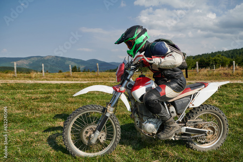 Fototapeta Naklejka Na Ścianę i Meble -  A motorcyclist equipped with professional gear, rides motocross on perilous meadows, training for an upcoming competition.