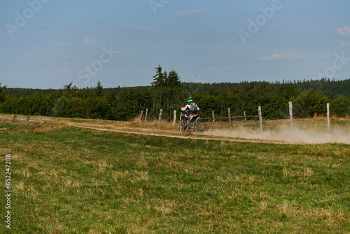 A professional motocross rider exhilaratingly riding a treacherous off-road forest trail on their motorcycle. photo