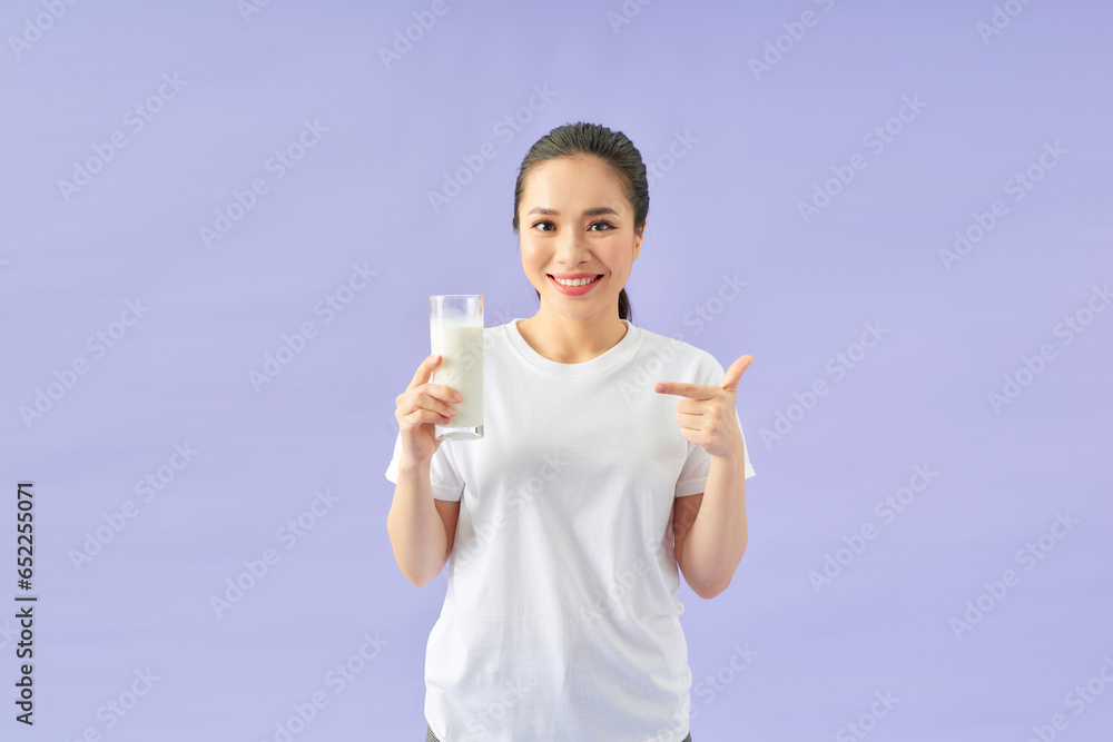 Young smiling happy woman wear white clothes hold in hand point finger on glass drink milk Young smiling happy woman wear white clothes hold in hand point finger on glass drink milk