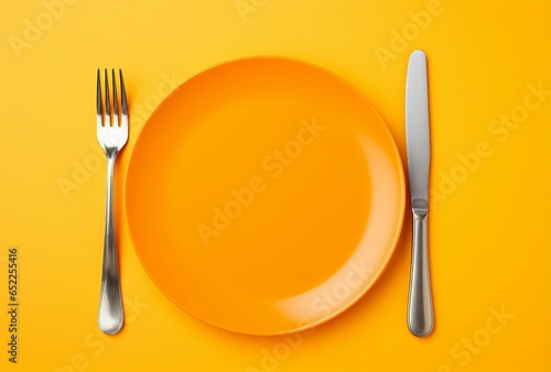 Fototapeta Naklejka Na Ścianę i Meble -  A yellow plate with a knife and fork