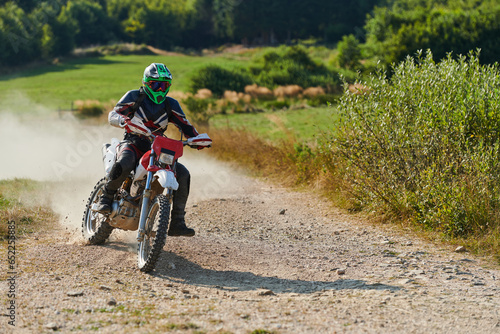 Fototapeta Naklejka Na Ścianę i Meble -  A professional motocross rider exhilaratingly riding a treacherous off-road forest trail on their motorcycle.