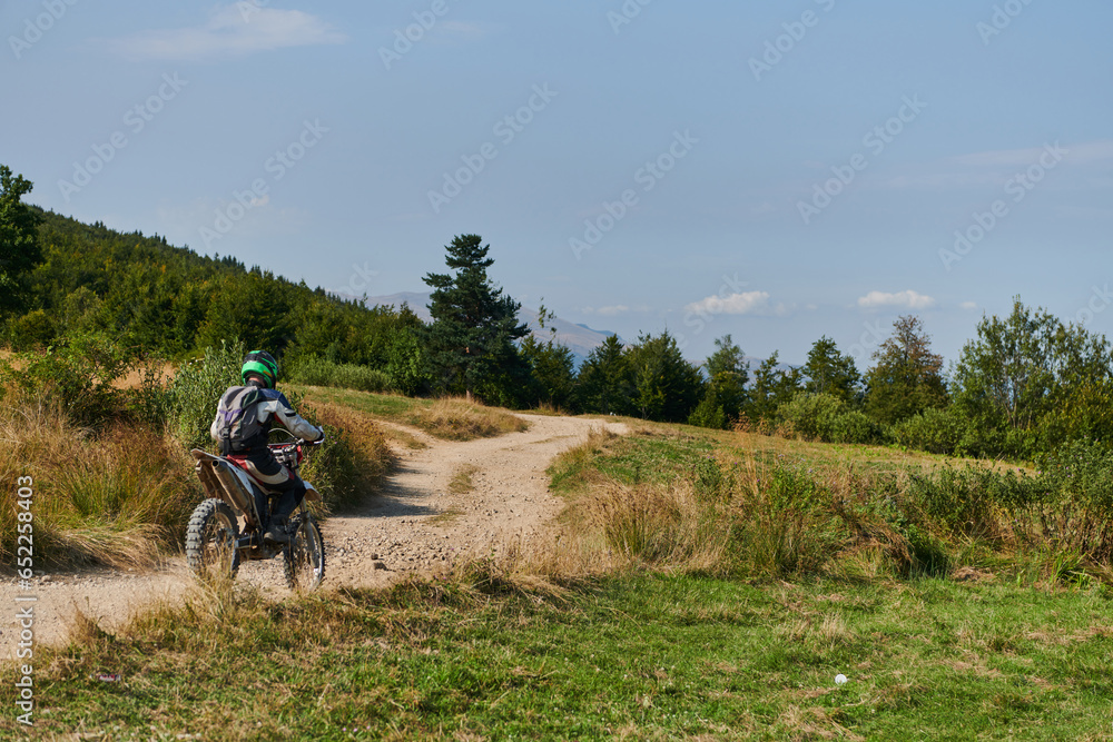 Obraz premium A professional motocross rider exhilaratingly riding a treacherous off-road forest trail on their motorcycle.