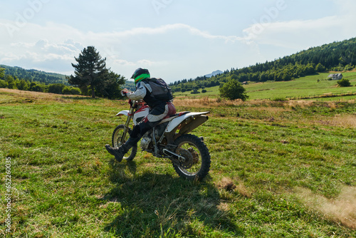 A motorcyclist equipped with professional gear, rides motocross on perilous meadows, training for an upcoming competition.