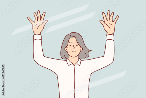 Sad woman raises hands standing behind transparent glass, symbolizing barrier to success