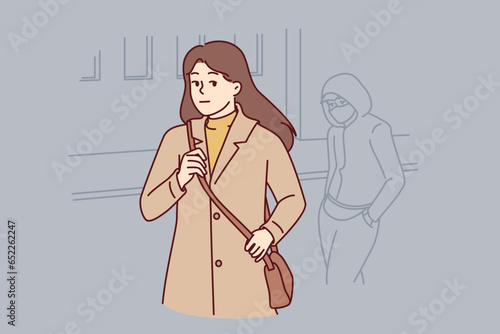 Woman walking through city at night notices stalker who wants to attack or rob defenseless girl. Lady is frightened looking back watching stalker, and needs protection of police or people passing by