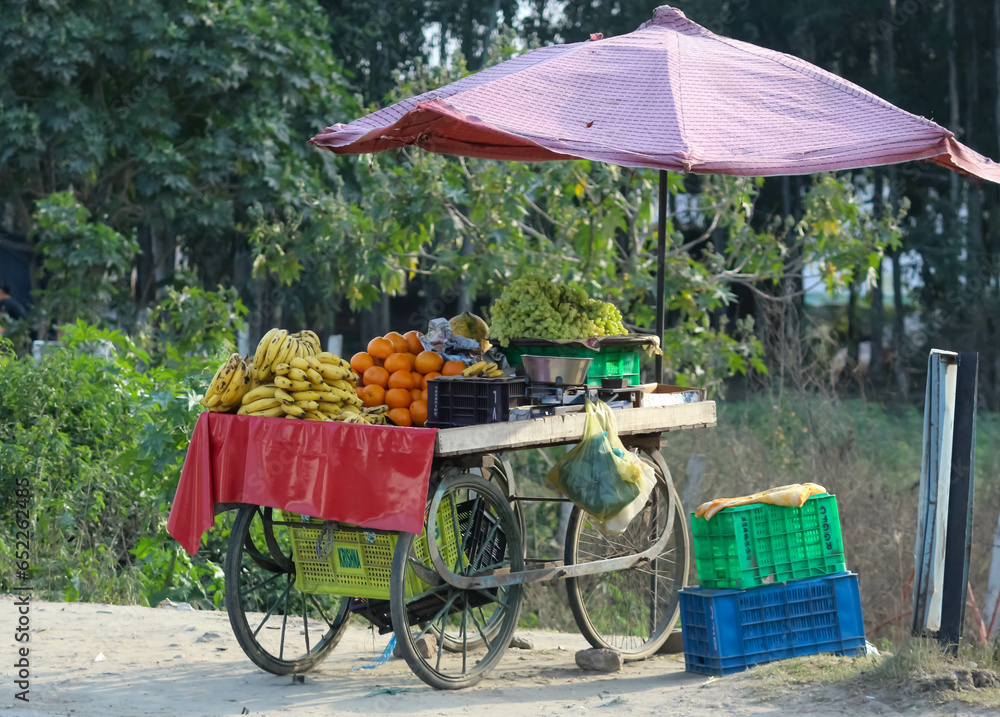 A fruit cart on the roadside in the city. Fresh seasonal fruits. street vendor hard work
