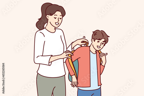 Mother helps son get ready for school and put on backpack with textbooks and office supplies. Schoolboy prepares for september 1 and hurries to school with smile, wanting to get quality education