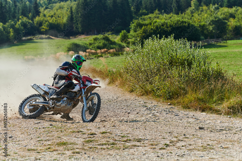 A professional motocross rider exhilaratingly riding a treacherous off-road forest trail on their motorcycle.