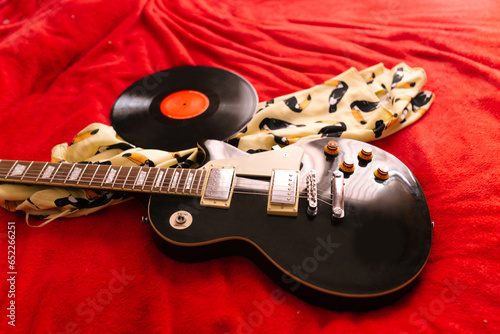 Vinyl record and electric guitar on bed
