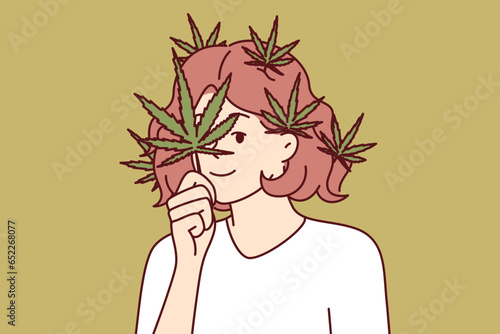 Woman with cannabis petals on face and hair calls for legalization of marijuana for medical and recreational purposes. Girl decorates hair with cannabis, wanting to prove advantage of using cannabis