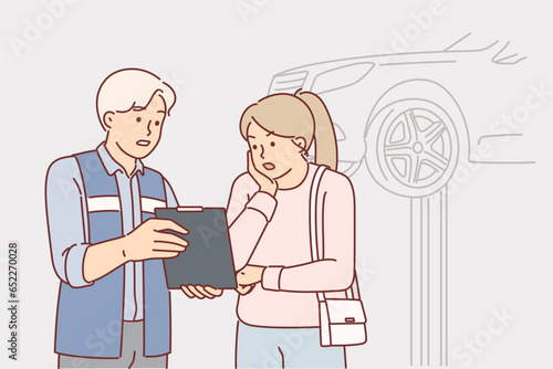 Auto mechanic showing repair cost to shocked woman client while standing in garage with car