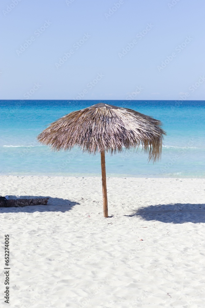 Bright beach umbrella in the sand on a sunny day, with a bright blue sky above