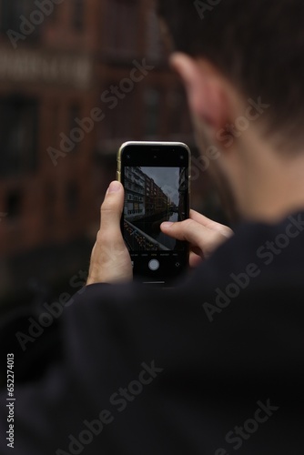 Man capturing a photo of a tall, modern building with his smartphone