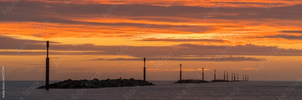 Breathtaking panoramic view of a bright orange sunrise over the horizon of Sea Palling