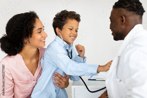 Latin Woman And Her Son Visiting General Practitioner At Clinic