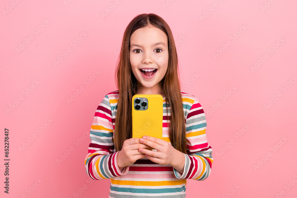 Photo of little young school kid received her first apple smartphone expensive device present surprise isolated on pink color background Photo of little young school kid received her first apple smartphone expensive device present surprise isolated on pink color background