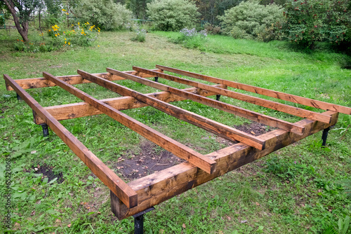 Foundation made of timber coated with antiseptic for a wooden frame house on screw metal piles