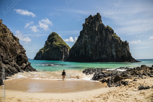 Woman standing on the beach and looking at cliffs. Cacimba do Padre, Fernando de Noronha, Brazil. photo