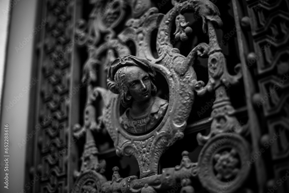 Black and white stock photo captures an ornamental metal door with intricate detailing