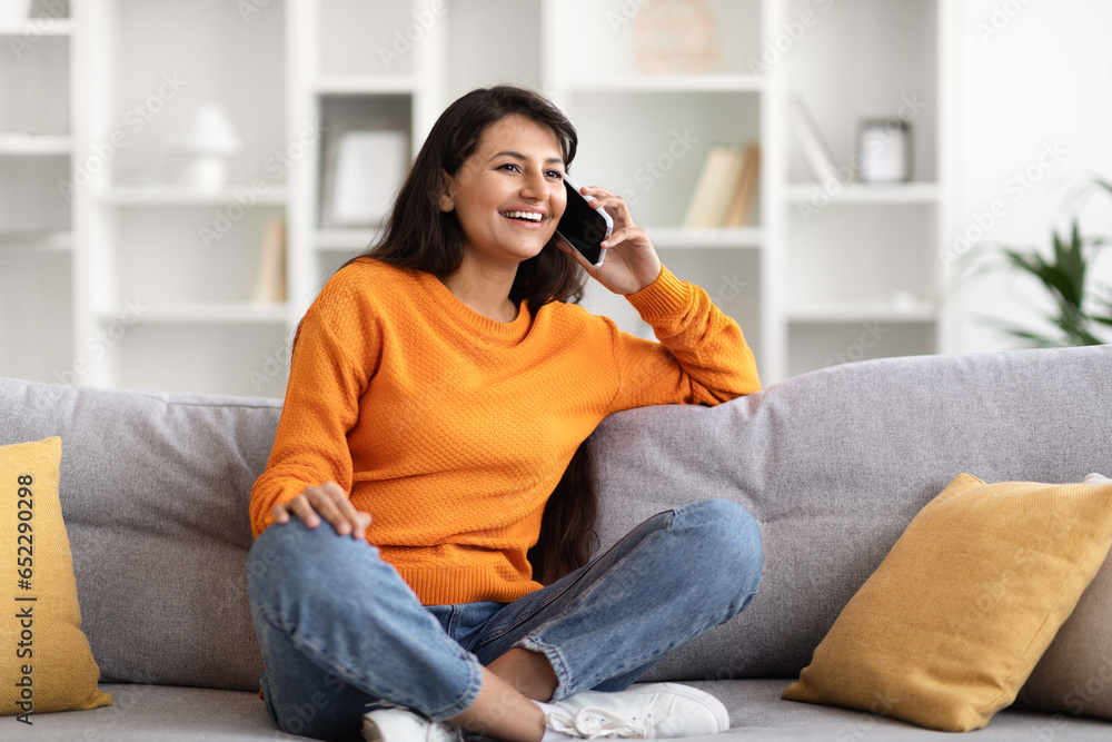 Smiling pretty young indian woman talking on phone at home Smiling pretty young indian woman talking on phone at home