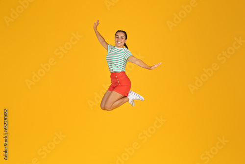 Carefree positive young woman jumping in the air on yellow