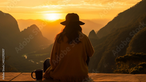 Frau mit Kaffee beim Sonnenaufgang in den Bergen