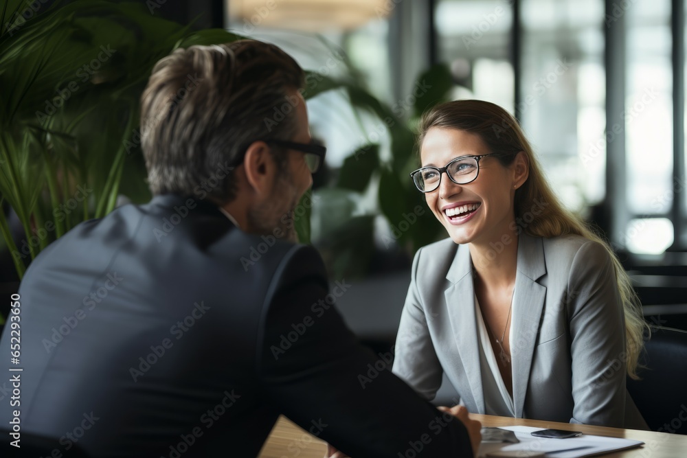 Portrait of happy businesswoman and businessman sitting at table in office