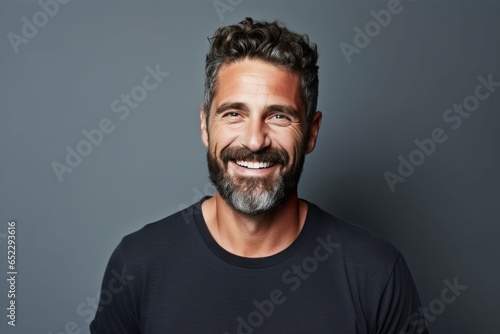 Portrait of a handsome young man smiling at the camera while standing against beige background