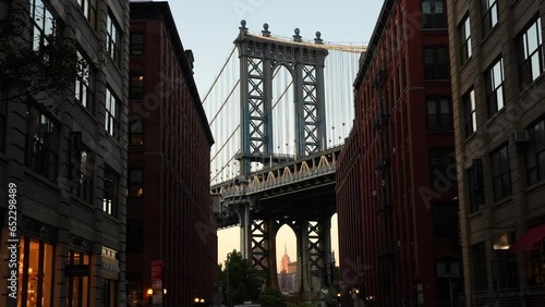 New York, USA - 3 September 2023: 4K wide angle video during a sunset over New York, view from Dumbo area in Brooklyn with Empire States landmark building under Manhattan Bridge.