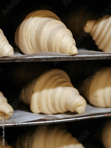 Raw croissant blanks before baking on baking sheets in a rack in a bakery
