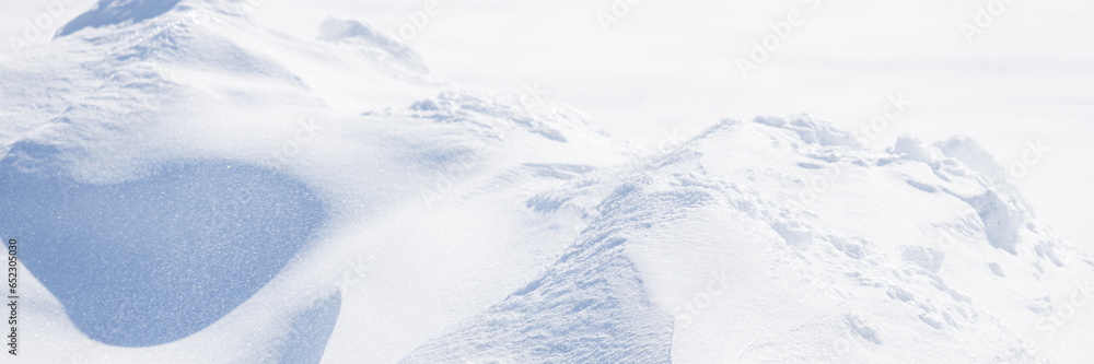 Obraz premium Beautiful winter background with snowy ground. Natural snow texture. Wind sculpted patterns on snow surface. Arctic, Polar region.