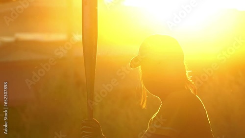 Female Softball Player Batting Ball with sunset