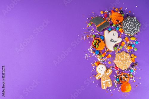Bright colorful Halloween gingerbread cookies and sweet background. Homemade biscuits with cookie cutters, sugar sprinkles and candies. High-colored Halloween treats flat lay top view copy space