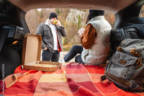 couple sitting in car trunk having picnic resting at nature