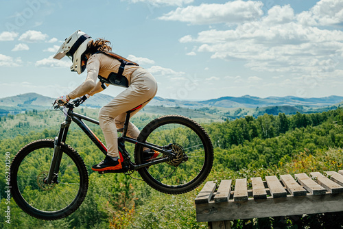 Canvas Print female athlete mountainbiker jump drop downhill in flight