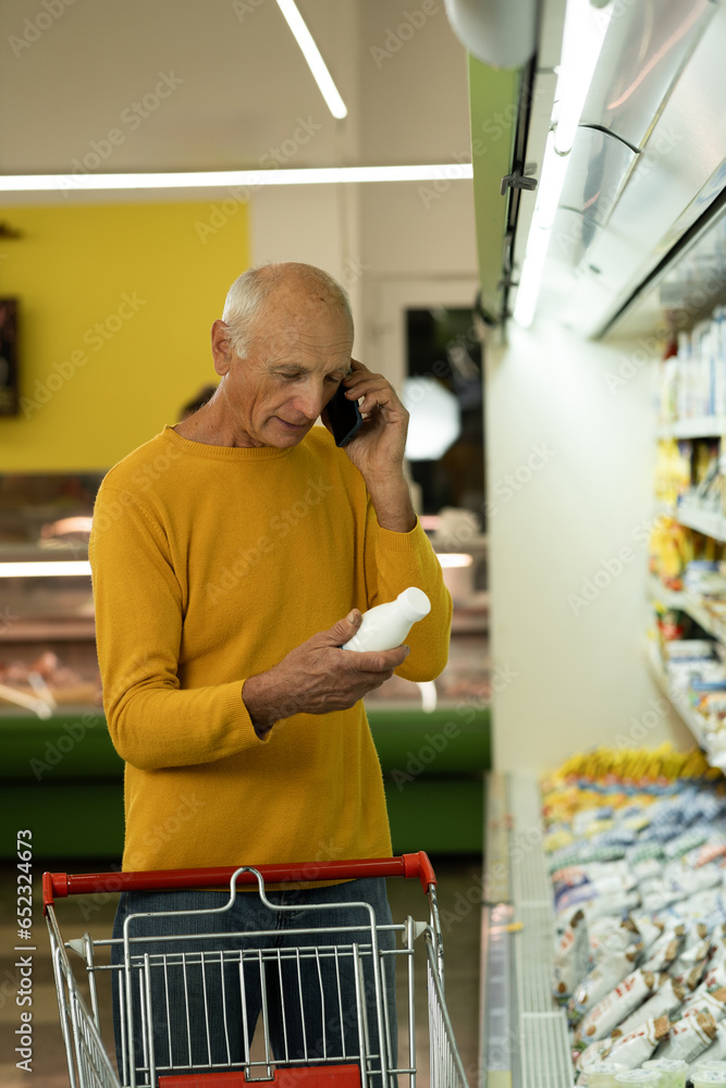 Old man choosing products on grocery shopping buying food in