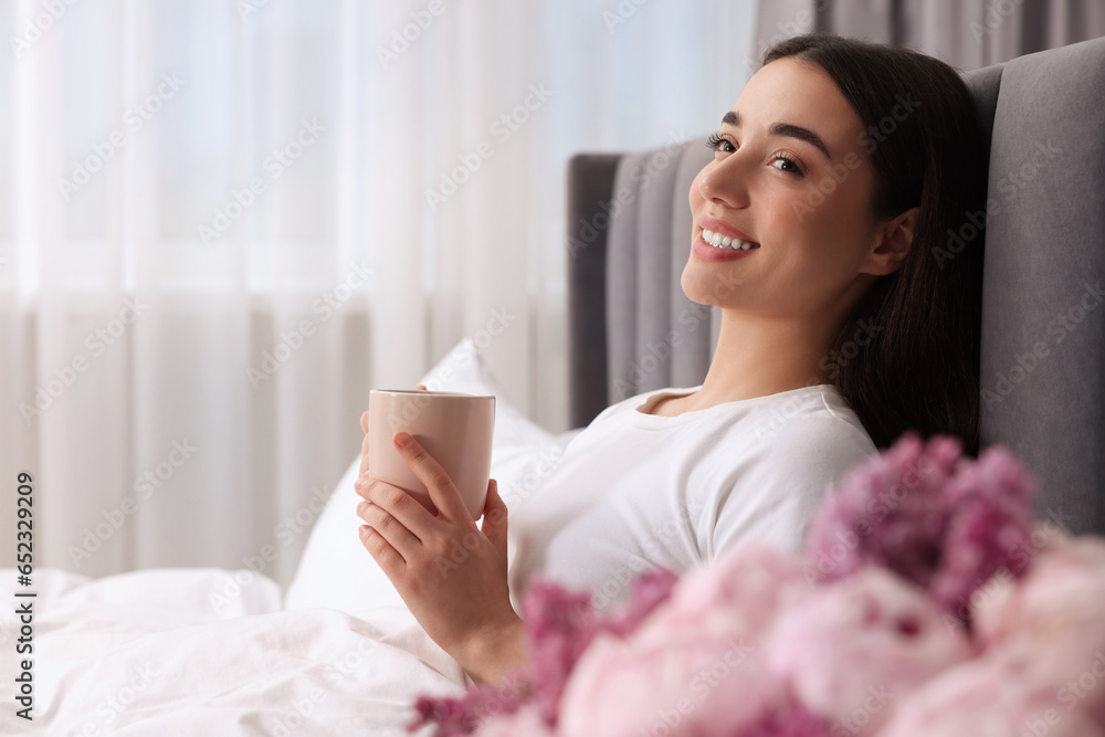 Happy woman with cup of drink in bed at home, space for text. Lazy morning Happy woman with cup of drink in bed at home, space for text. Lazy morning