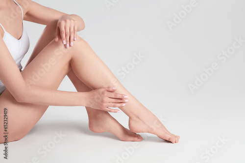 Woman with beautiful smooth legs on white background, closeup. Space for text