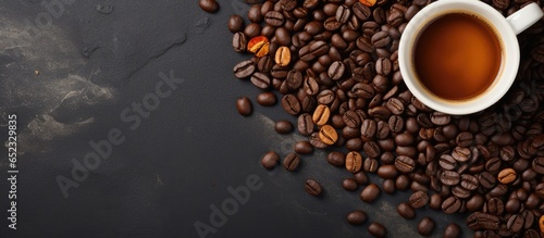 Top view image of a dark stone background with a cup of coffee and coffee beans on a horizontal banner with copy space