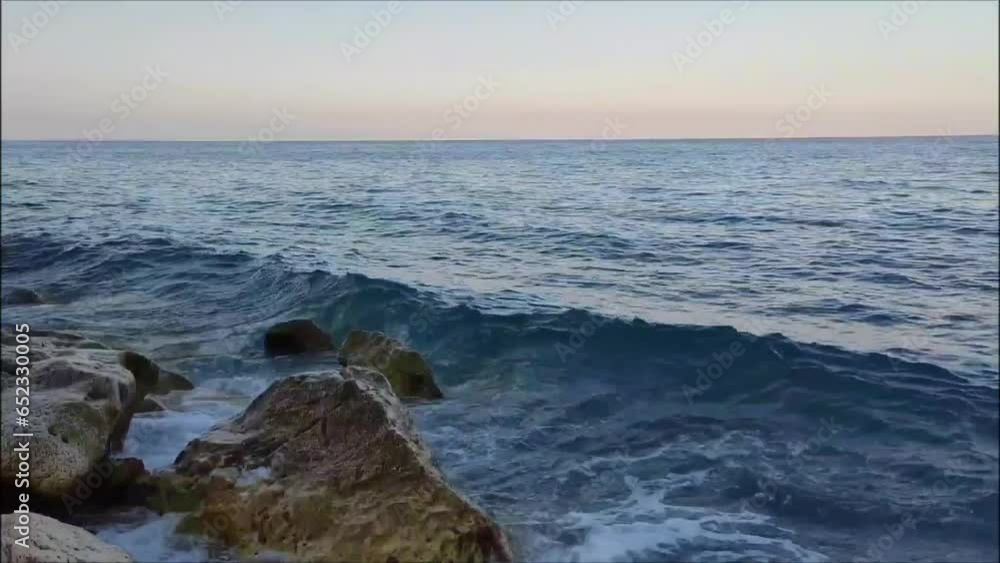 Strong waves of the blue Mediterranean Sea come to the sandy shore with large stones Strong waves of the blue Mediterranean Sea come to the sandy shore with large stones