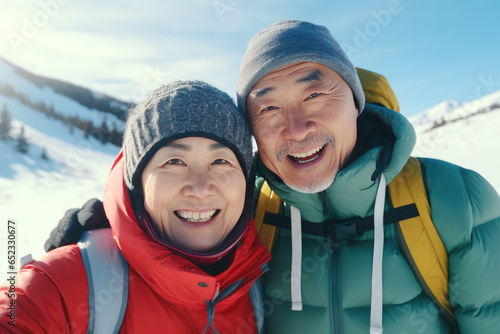 Portrait of two Asian pensioners hiking in the winter mountains. Healthy lifestyle for older people.