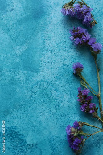 Limonium sinuatum, commonly known as wavyleaf sea lavender, statice, sea lavender, notch leaf marsh rosemary, sea pink flowers on a blue watercolor background photo